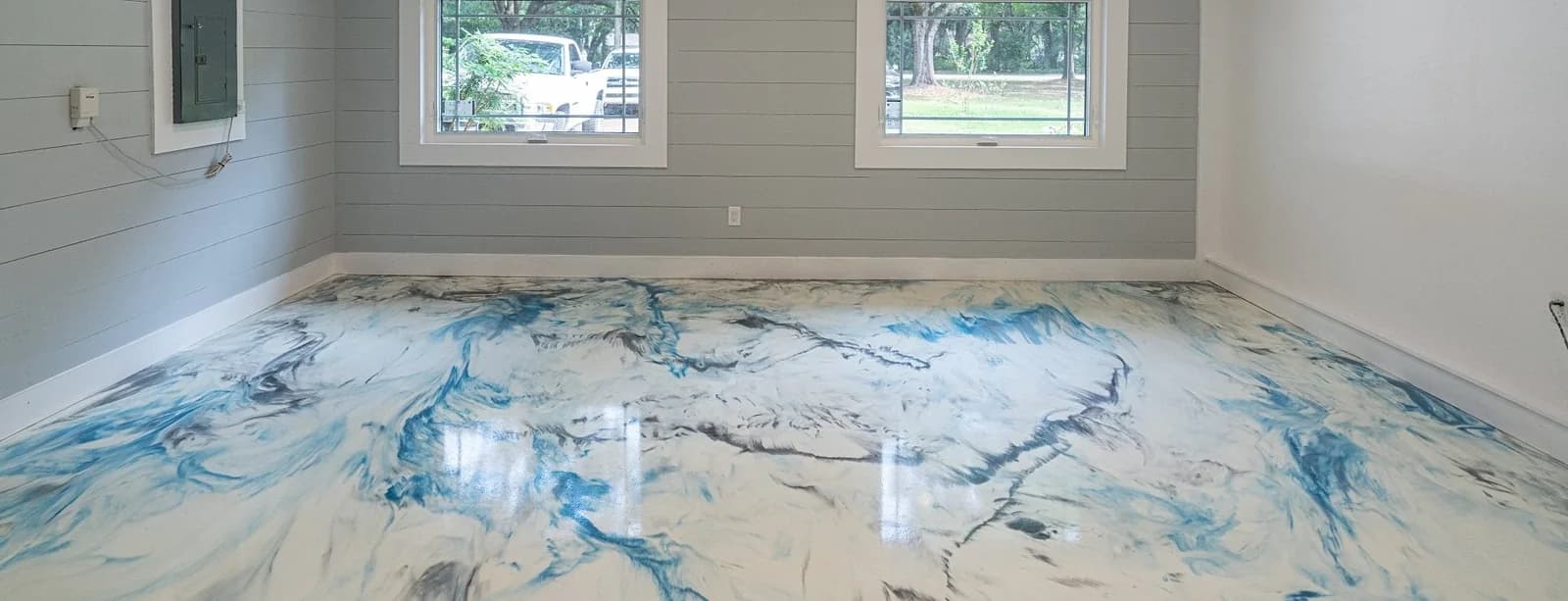 A home room with a white and blue marble metallic epoxy floor under two windows